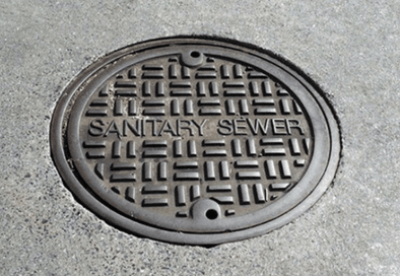 Image of sewer manhole cover with words sanitary sewer across